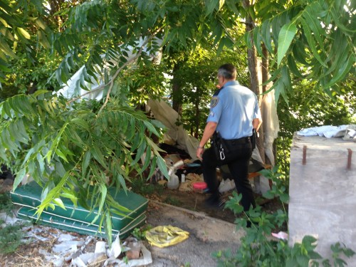 Officer Giraldo checking on the welfare of a homeless man in a makeshift tent.